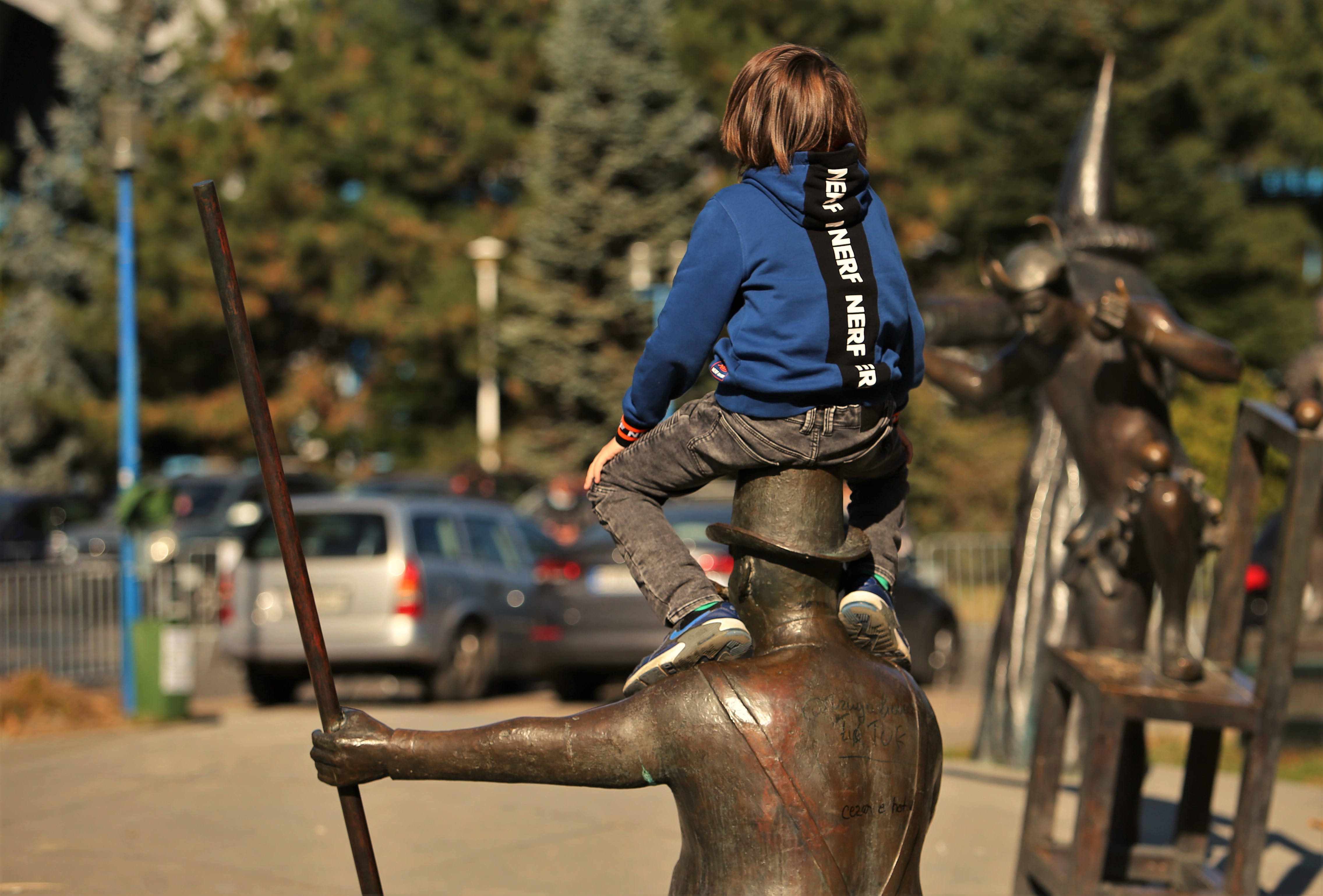 Un băiat cățărat pe capul unei statui